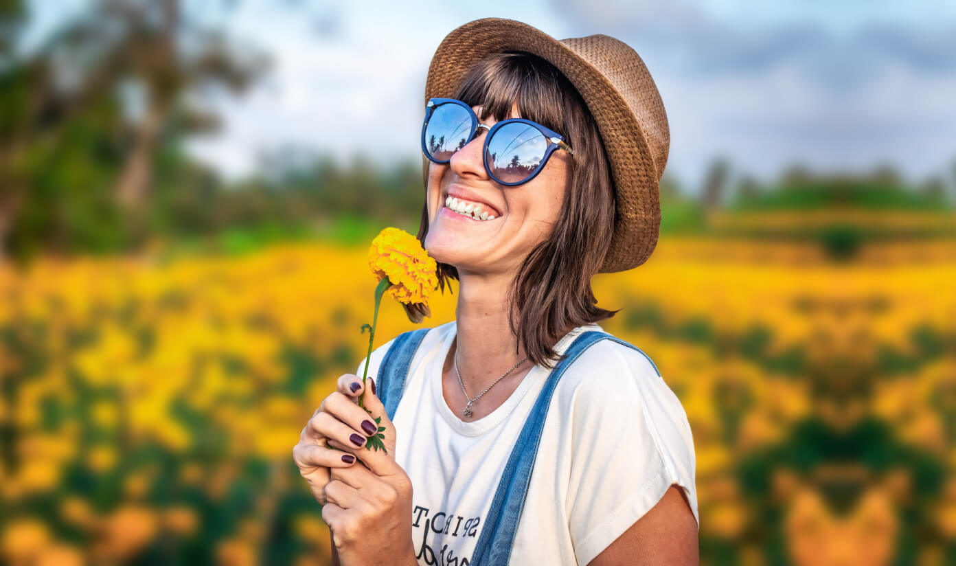 Blur background image of girl with hat holding marigold